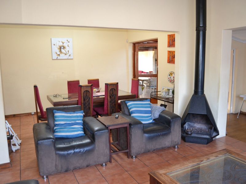 Open plan living and dining area featuring terracotta floor tiles and a prominent black freestanding fireplace.