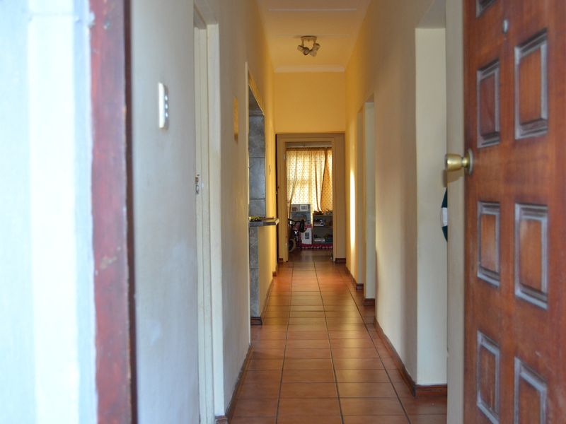 A functional interior hallway featuring tiled flooring and a wooden entrance door, providing access to adjacent rooms within the home.