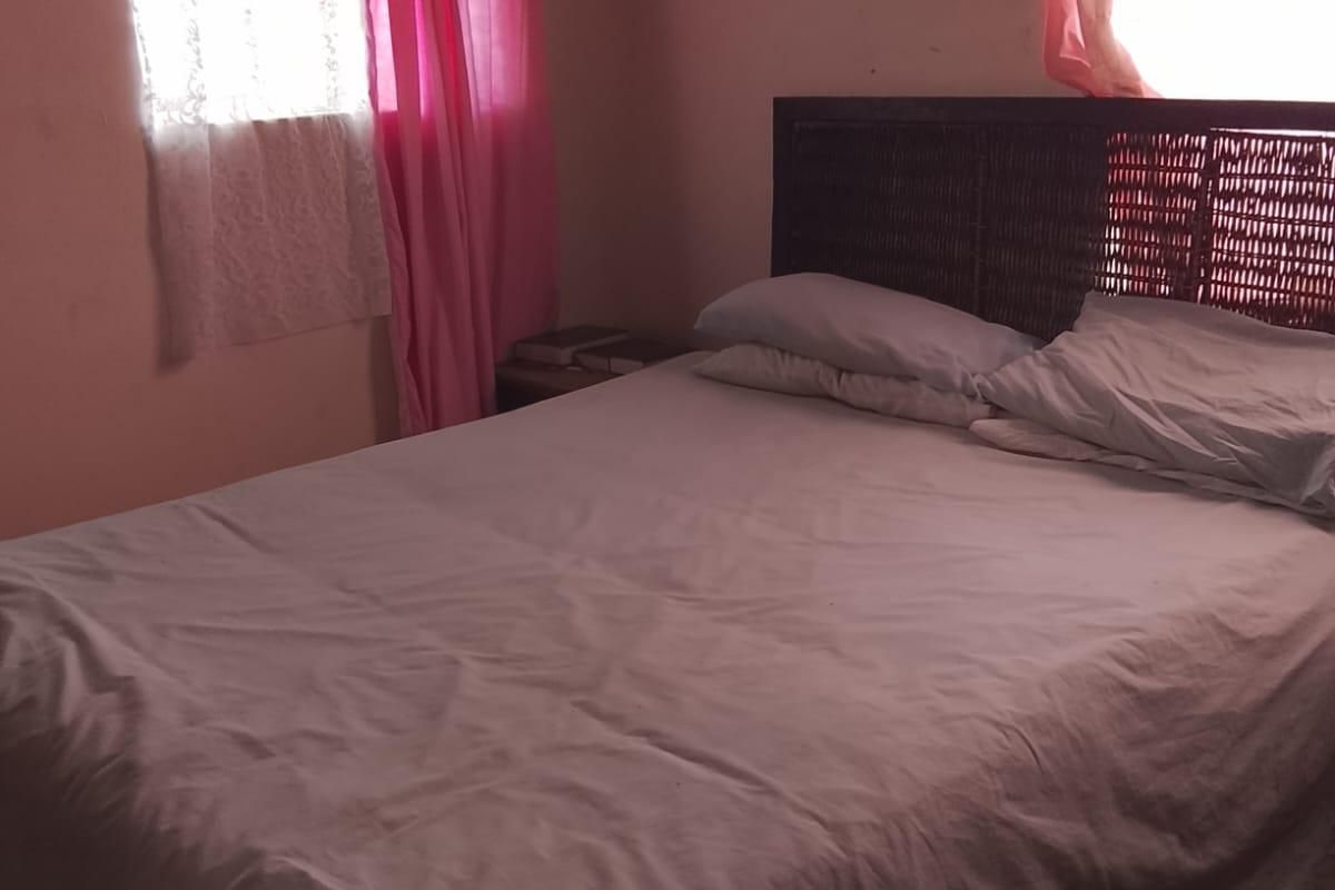 A bedroom featuring basic wall finishes and window security bars, requiring cosmetic updates to improve the overall aesthetic and condition.
