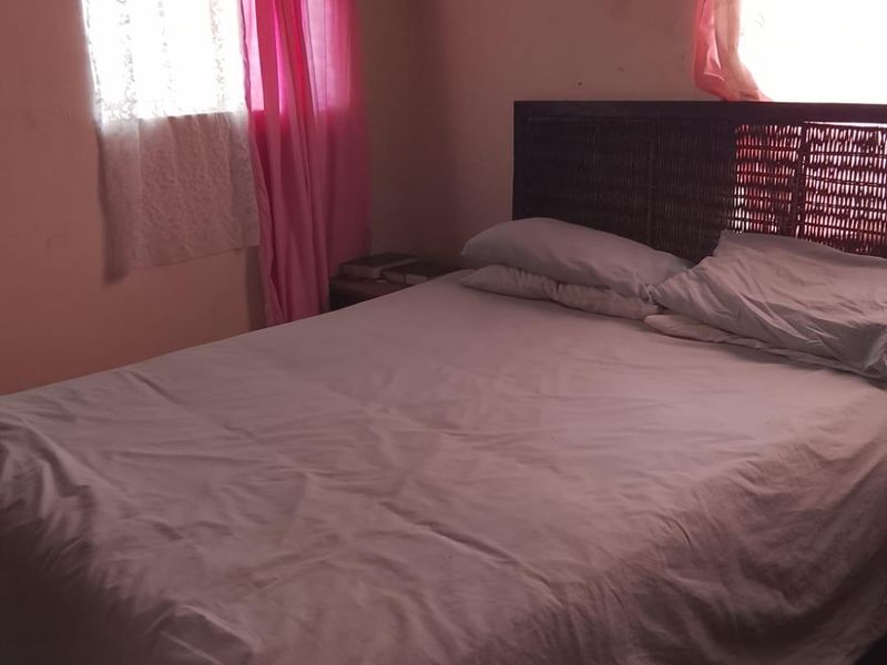 A bedroom featuring basic wall finishes and window security bars, requiring cosmetic updates to improve the overall aesthetic and condition.