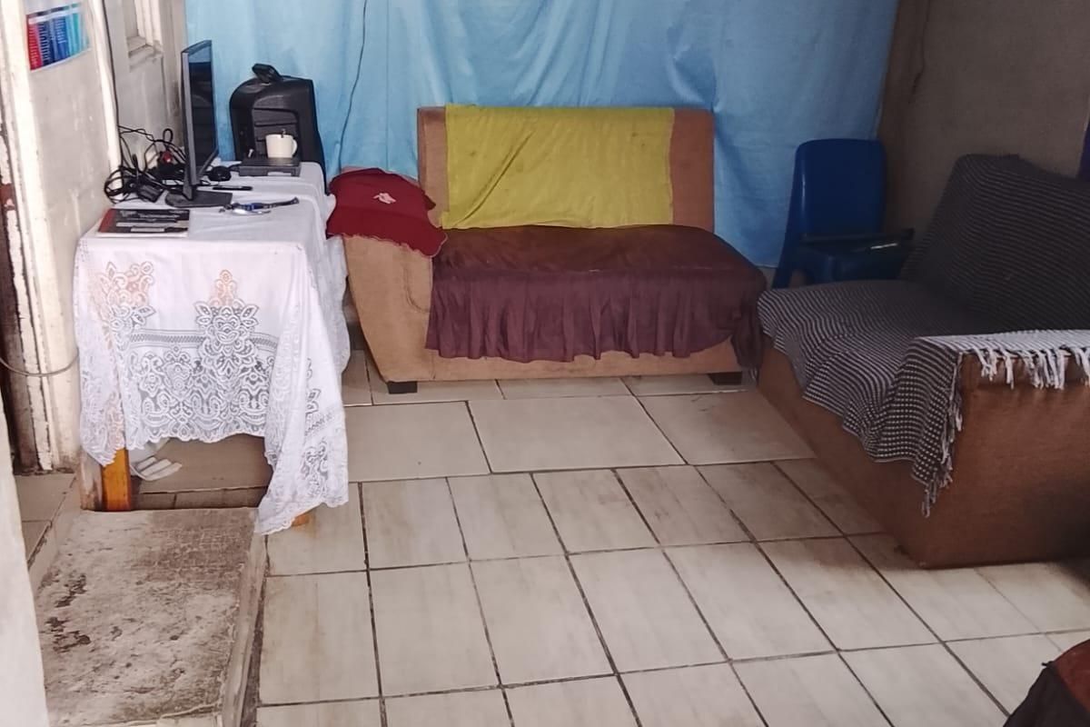 A living area featuring ceramic tiled flooring and a wall-mounted air conditioning unit, currently requiring cosmetic updates and wall finishing.