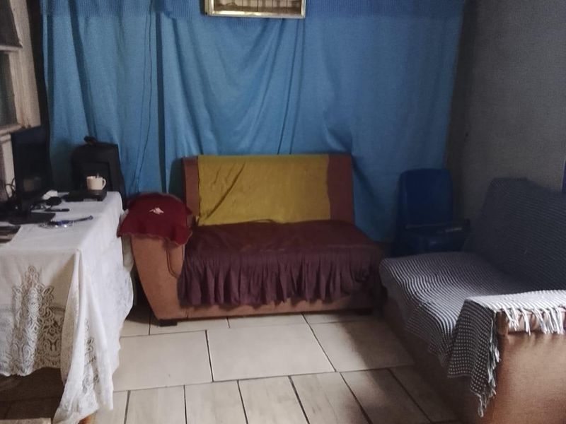 A living area featuring tiled flooring and unfinished wall and ceiling finishes, offering potential for renovation and modernization.
