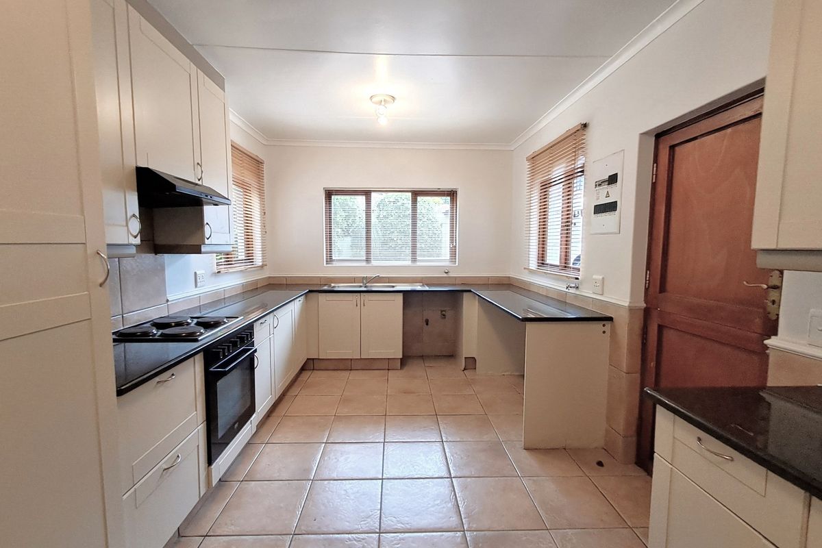 A functional kitchen featuring cream cabinetry, dark granite countertops, built-in oven and hob, and tiled flooring. The space is clean and ready for customization.
