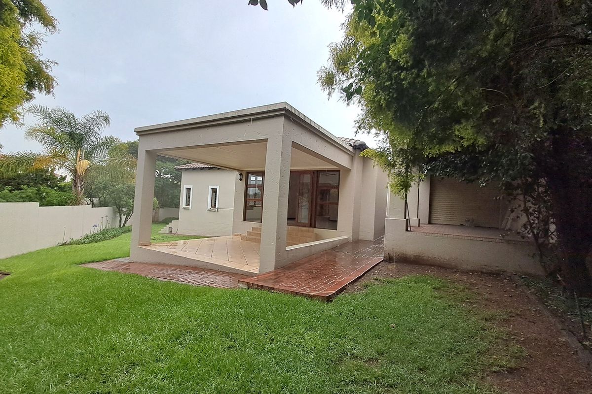 Rear view of the property featuring a covered patio with tiled flooring, a brick pathway, and a well-maintained lawn area.