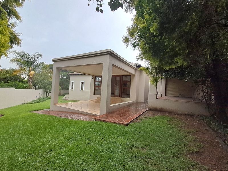 Rear view of the property featuring a covered patio with tiled flooring, a brick pathway, and a well-maintained lawn area.