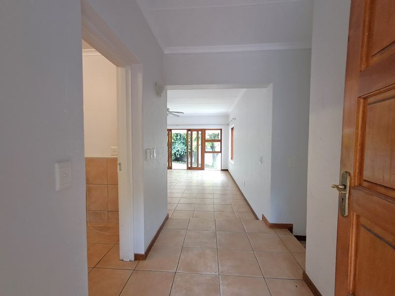 A bright, tiled hallway leading into an open-plan living area with sliding glass doors providing access to the exterior.