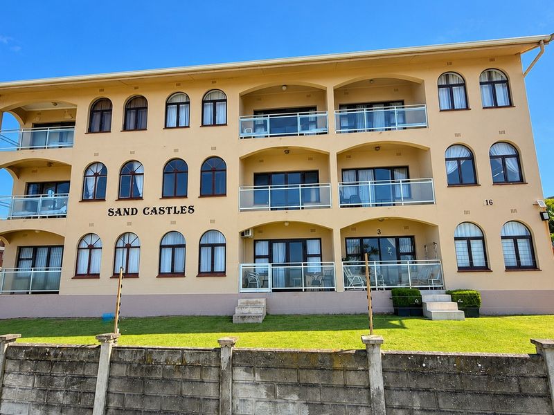 Front elevation of the Sand Castles apartment complex, featuring three levels of balconies with glass balustrades and arched windows.