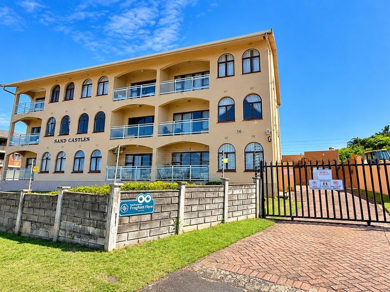 Front elevation of the Sand Castles apartment complex, featuring a multi-story facade with arched windows, private balconies, and a secure gated entrance.