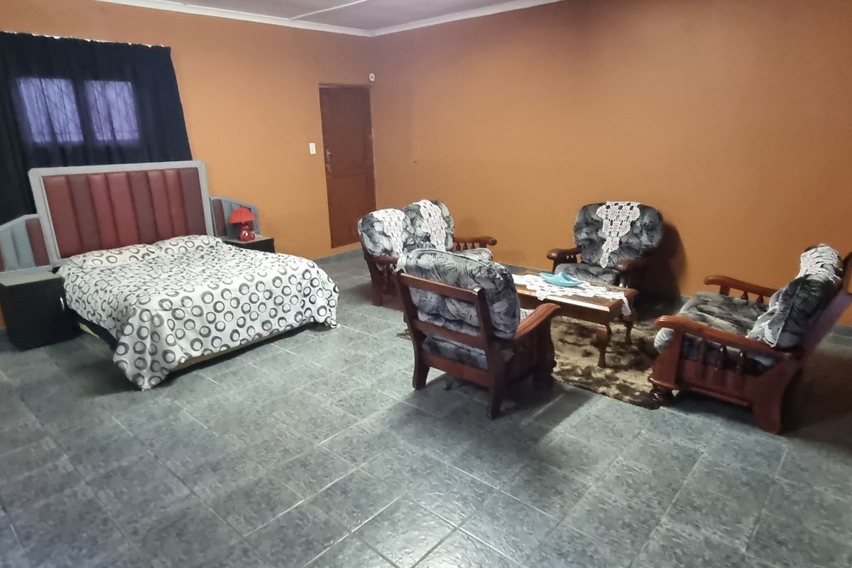 Spacious bedroom featuring tiled flooring and neutral wall finishes, offering a versatile layout for sleeping and seating arrangements.