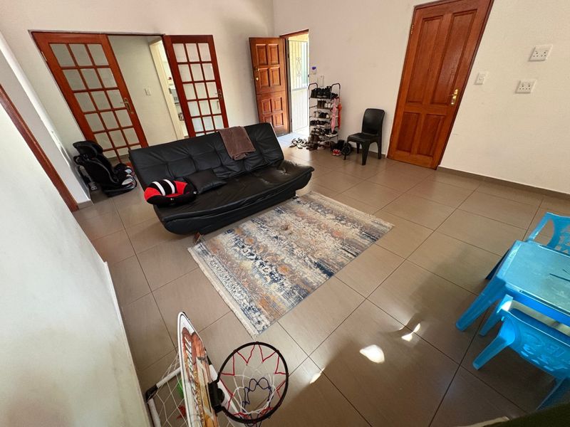 A living room area featuring neutral tiled flooring and traditional wooden doors, providing a functional and versatile space for family living.