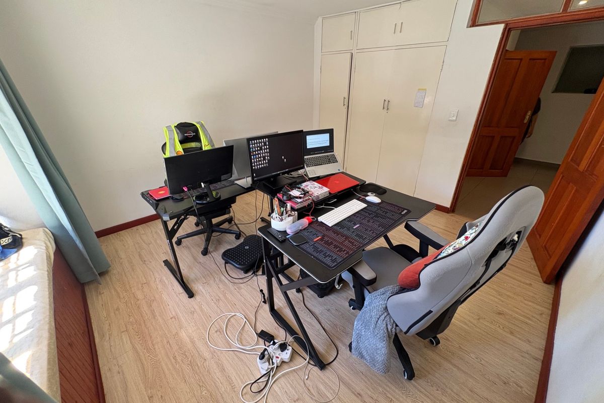 A bedroom featuring laminate flooring and built-in cupboards, currently utilized as a home office space.