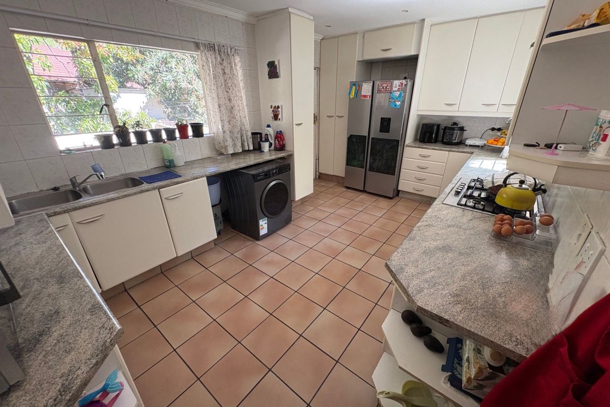 Functional kitchen featuring ample built-in cabinetry, laminate countertops, a gas hob, and tiled flooring with a large window providing natural light.