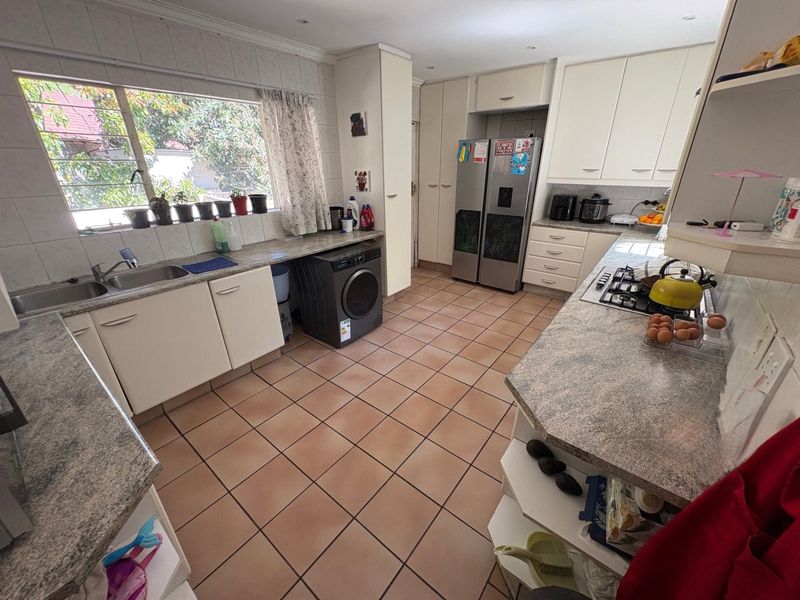 Functional kitchen featuring ample built-in cabinetry, laminate countertops, a gas hob, and tiled flooring with a large window providing natural light.