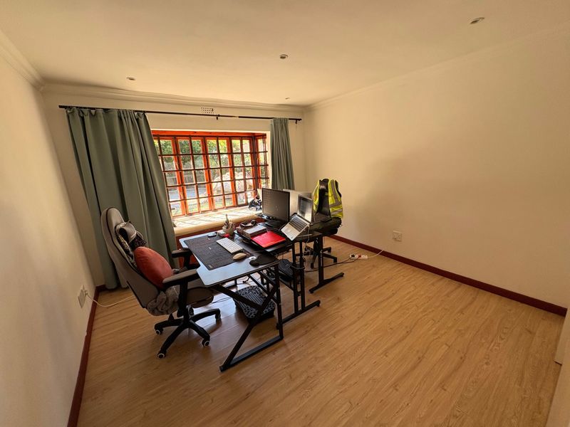 A bright home office featuring laminate flooring, recessed lighting, and a large bay window that provides ample natural light.