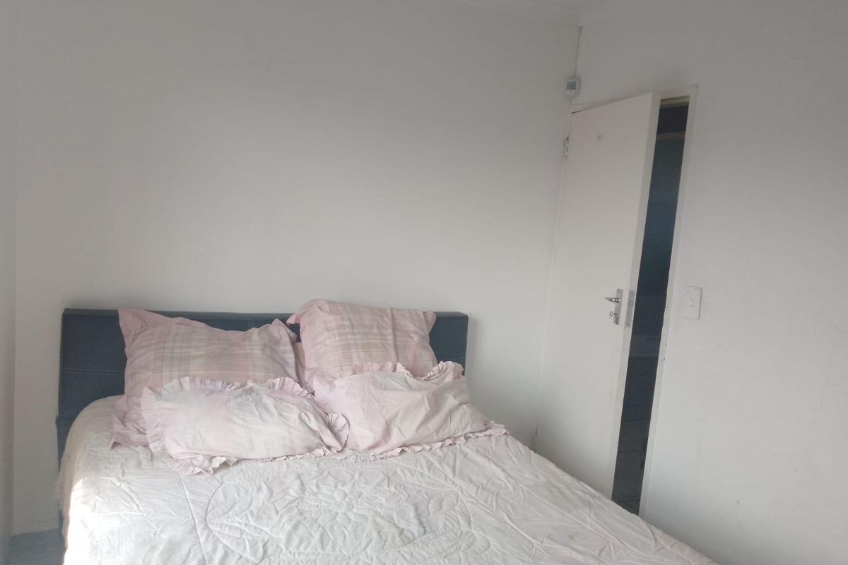 A simple bedroom featuring plain white walls and an internal door leading to an adjacent space.