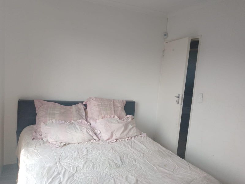 A simple bedroom featuring plain white walls and an internal door leading to an adjacent space.