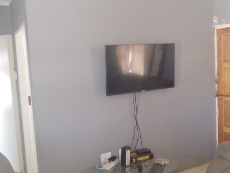 A living room area featuring tiled flooring and grey painted walls with visible ceiling cornice detailing.