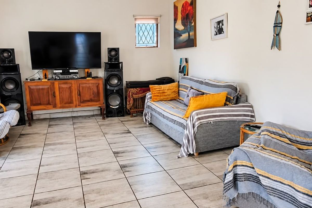 A spacious living room featuring neutral tiled flooring and a small leaded glass window, providing a functional and well-lit area for relaxation.