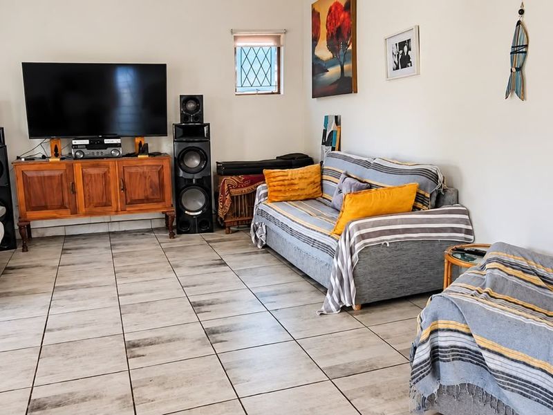 A spacious living room featuring neutral tiled flooring and a small leaded glass window, providing a functional and well-lit area for relaxation.