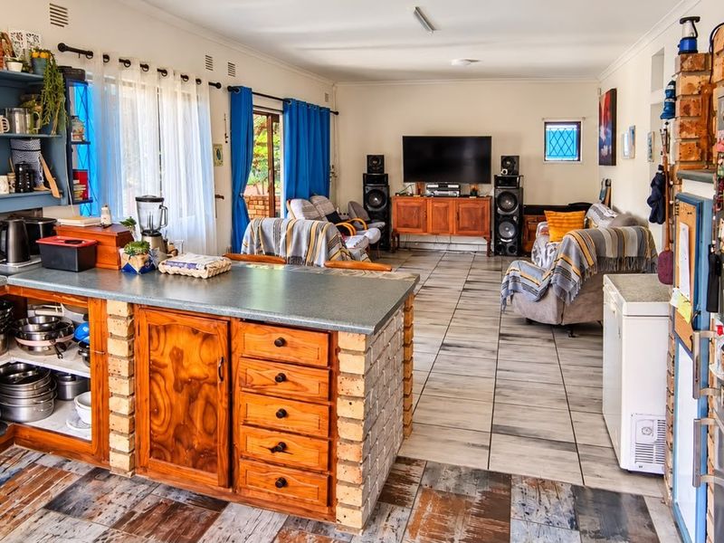 Open-plan living and kitchen area featuring a brick-base island, built-in oven, and tiled flooring throughout the combined space.