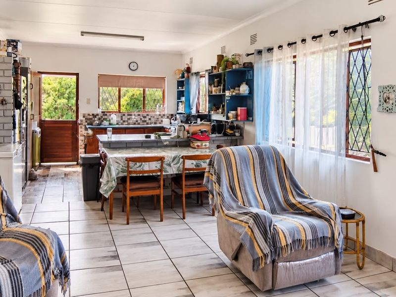 Open plan living and kitchen area featuring tiled flooring, an arched entryway, and functional kitchen cabinetry with a breakfast counter.