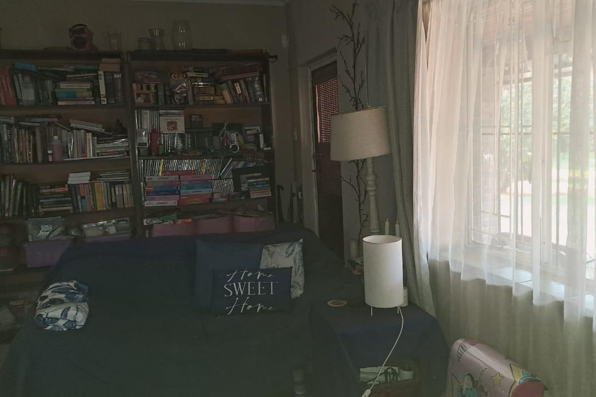 A living room area featuring tiled flooring and windows fitted with security bars, providing a functional space with natural light.