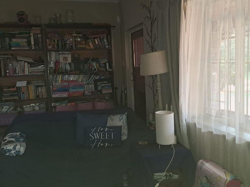 A living room area featuring tiled flooring and windows fitted with security bars, providing a functional space with natural light.