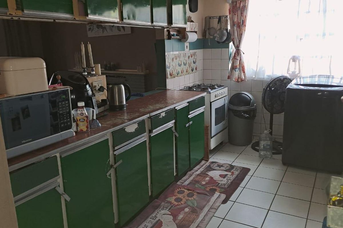 A functional kitchen featuring green built-in cabinetry, a gas stove, and tiled flooring, offering potential for a modern renovation.