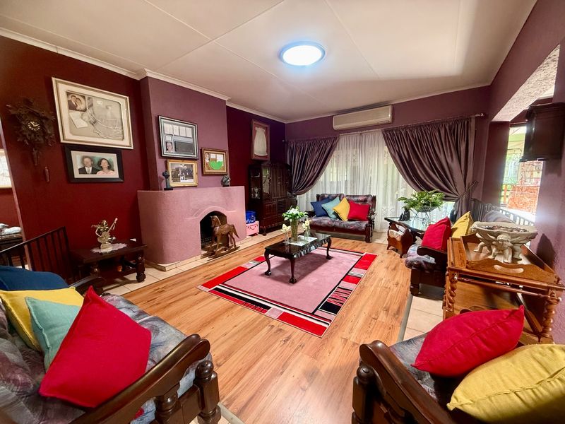 A cozy living room featuring a built-in fireplace, laminate flooring, and a wall-mounted air conditioning unit, providing a comfortable and functional living space.