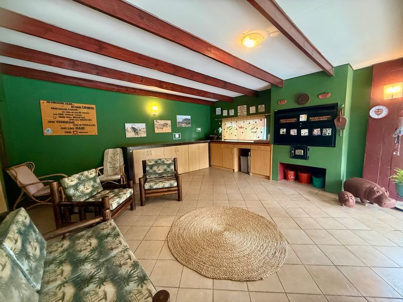 Spacious living area featuring exposed timber ceiling beams, tiled flooring, and a built-in fireplace with integrated cabinetry.