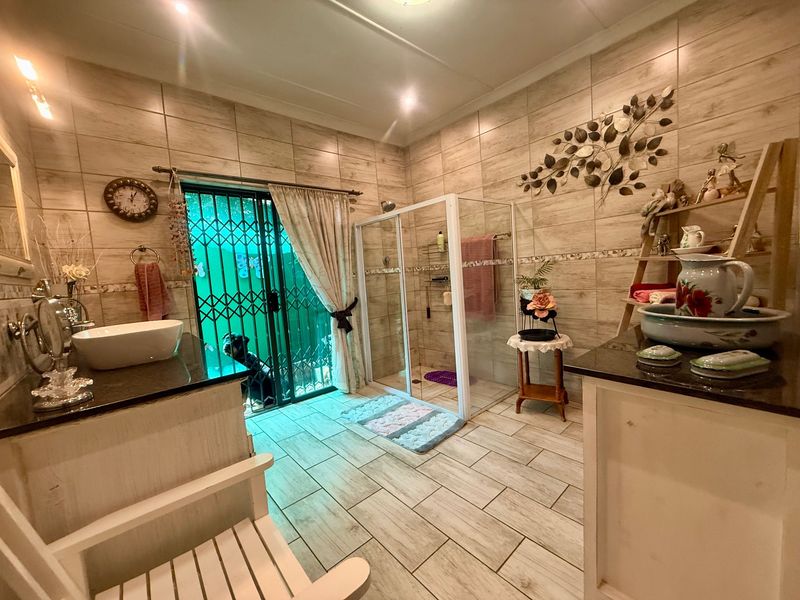 A well-maintained bathroom featuring wood-look ceramic tiling, a walk-in glass shower, and a vanity with a granite countertop.