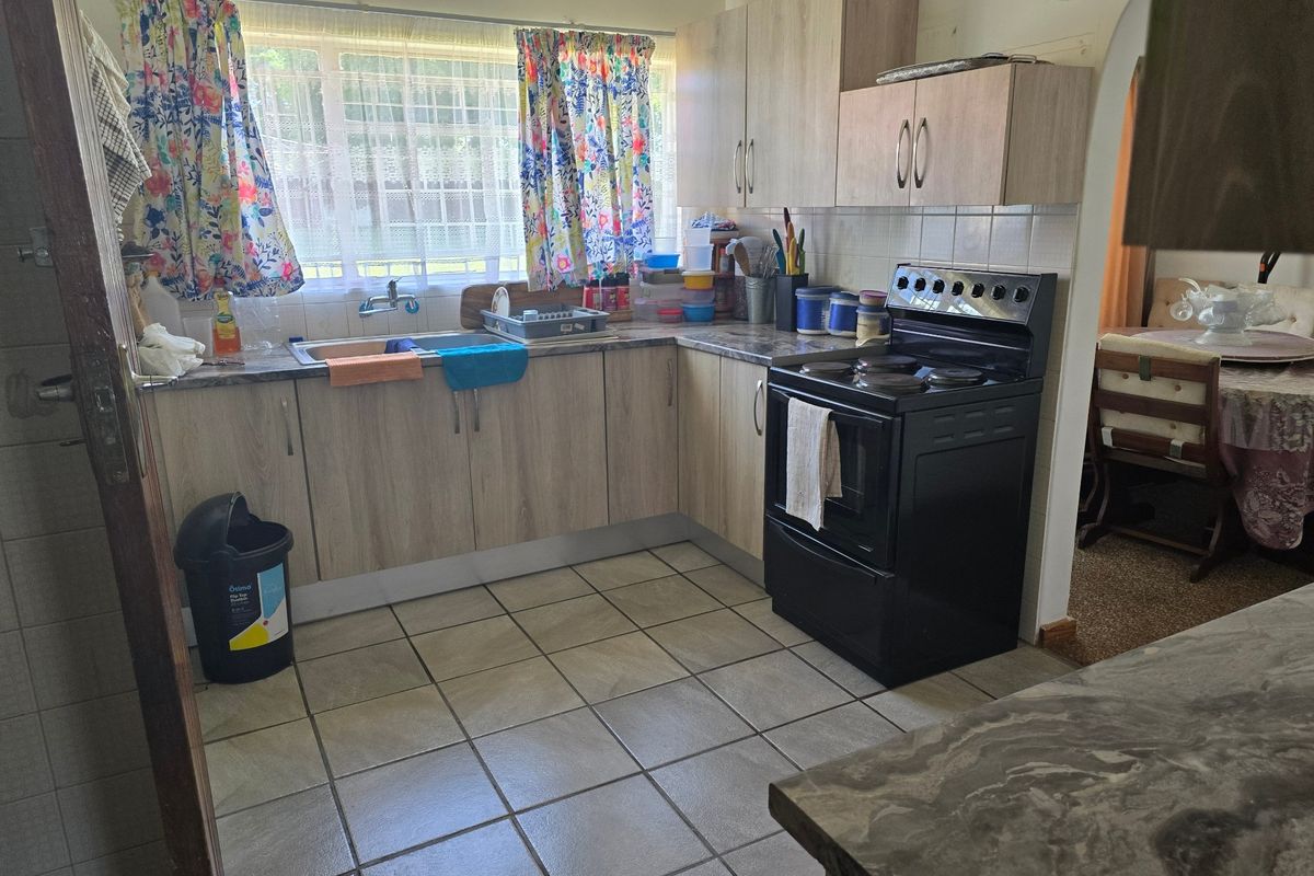 Functional kitchen featuring light wood-tone cabinetry, laminate countertops, tiled backsplash, and ceramic floor tiles, offering a practical layout for daily meal preparation.