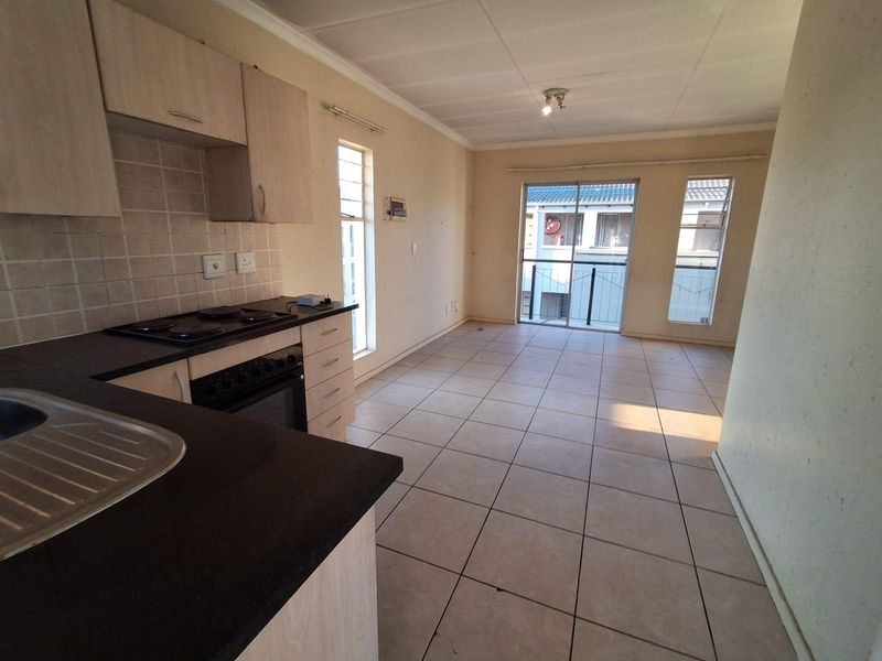 Open-plan kitchen and living area featuring tiled flooring, built-in cabinetry, and access to a balcony through sliding glass doors.