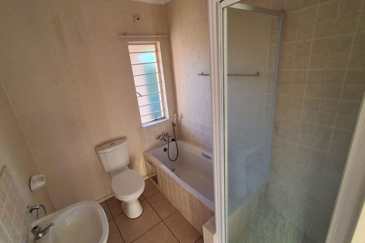 A functional bathroom featuring a bathtub, separate shower enclosure, toilet, and pedestal basin with tiled flooring and splashbacks.