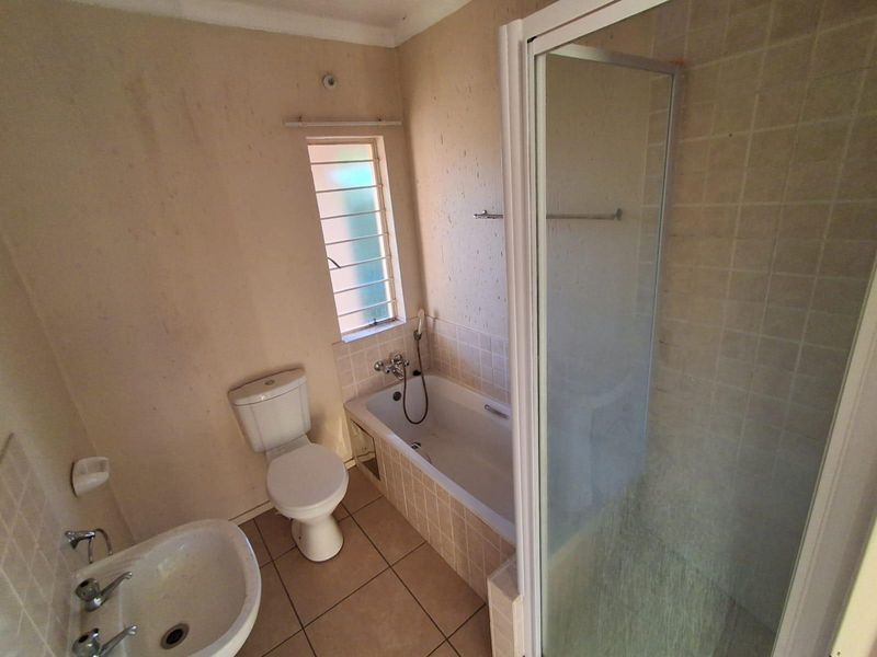 A functional bathroom featuring a bathtub, separate shower enclosure, toilet, and pedestal basin with tiled flooring and splashbacks.