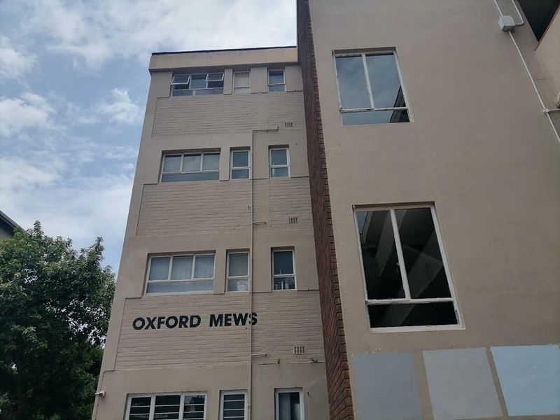 Exterior view of the Oxford Mews apartment building facade featuring multi-story brick construction and aluminum window frames.