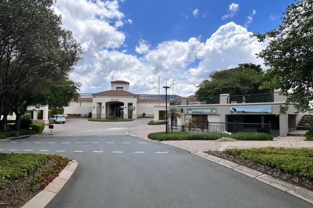 Exterior view of the Blue Valley clubhouse facility featuring a paved driveway, landscaped gardens, and integrated solar panels on the roof.