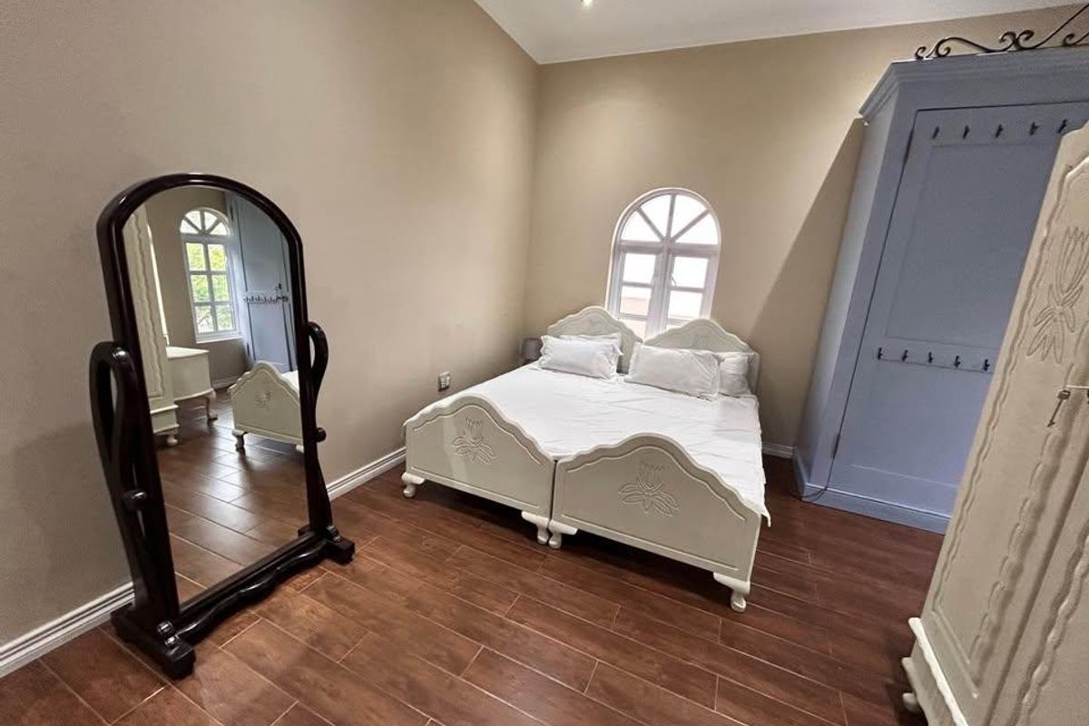 A well-maintained bedroom featuring tiled flooring, an arched window, and recessed lighting, providing a neutral and comfortable living space.