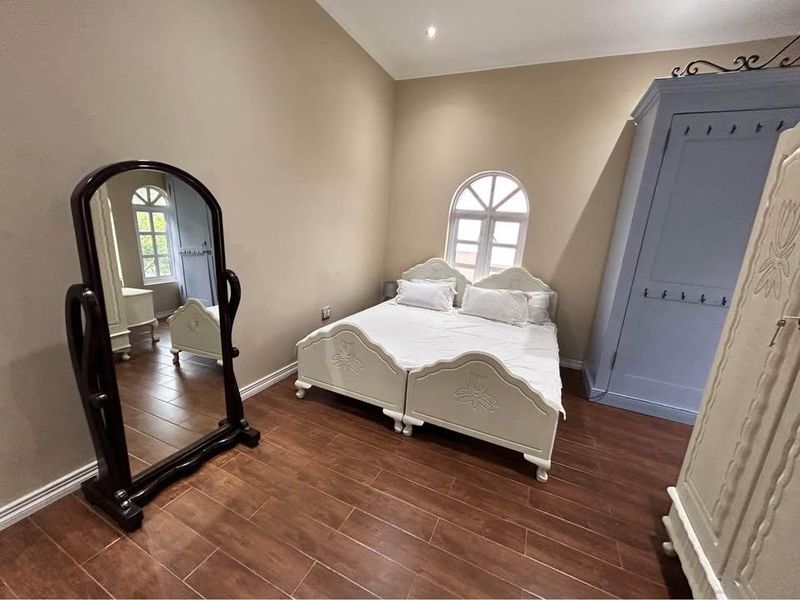 A well-maintained bedroom featuring tiled flooring, an arched window, and recessed lighting, providing a neutral and comfortable living space.