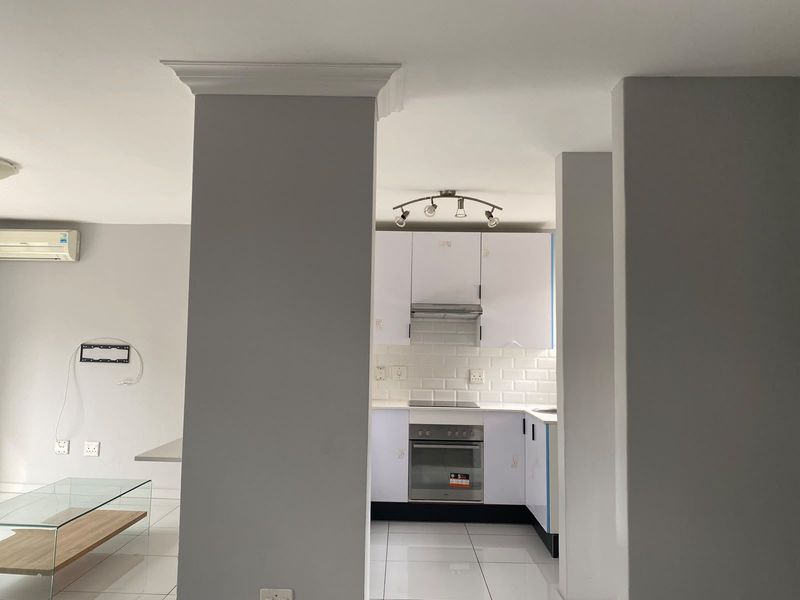 Open plan living area featuring a modern kitchen with subway tile backsplash, built-in oven, hob, and extractor fan, complemented by tiled flooring throughout.