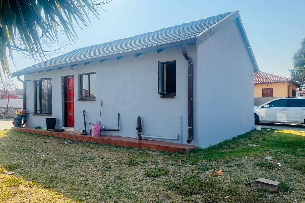 Rear view of the property featuring a tiled roof, exterior tiled patio, and security gate access.