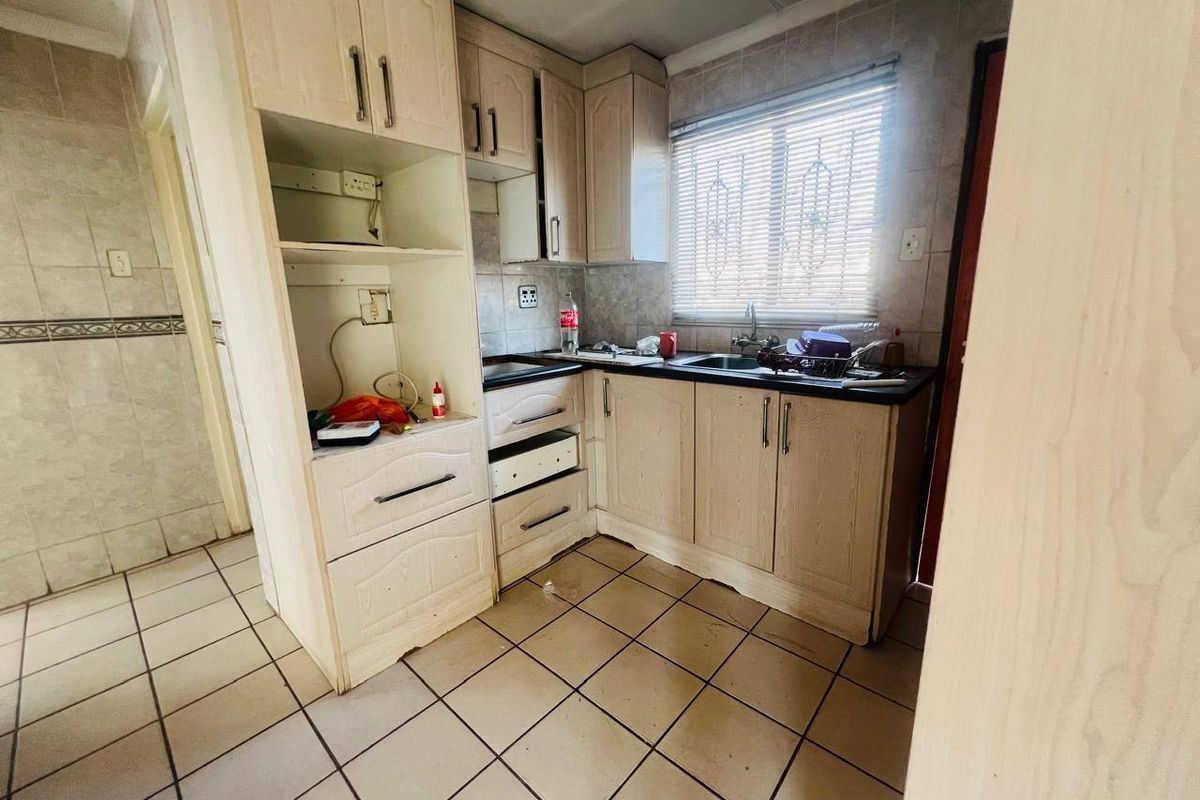 Compact kitchen featuring dated built-in cabinetry, tiled flooring, and a stainless steel sink, offering potential for a modern renovation.