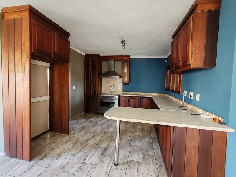 A spacious kitchen featuring wooden cabinetry, laminate countertops, and a built-in oven with an extractor fan, offering a functional layout ready for modern updates.