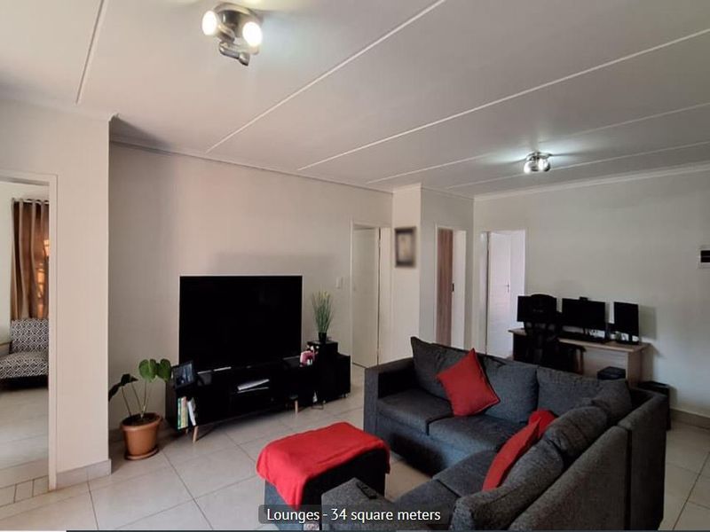 Spacious living area featuring neutral tiled flooring and multiple ceiling light fixtures, providing a versatile space for relaxation and entertainment.
