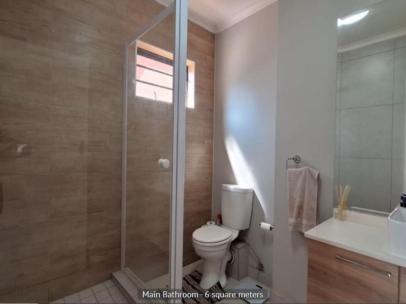 Modern bathroom featuring a walk-in shower with wood-look tile accents, a contemporary vessel sink vanity, and a large wall mirror.
