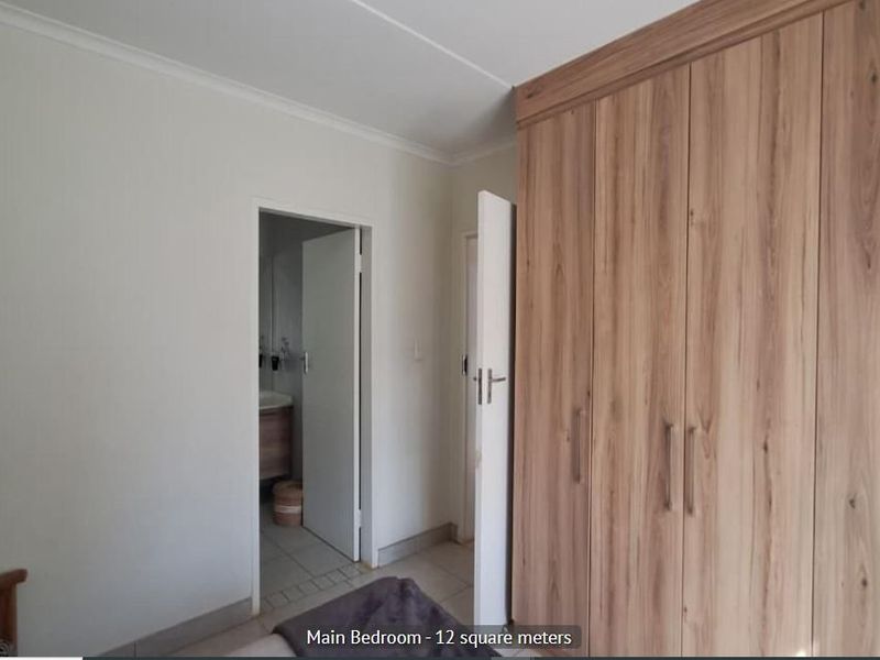 Bedroom featuring extensive built-in wooden cupboards and access to an en-suite bathroom.