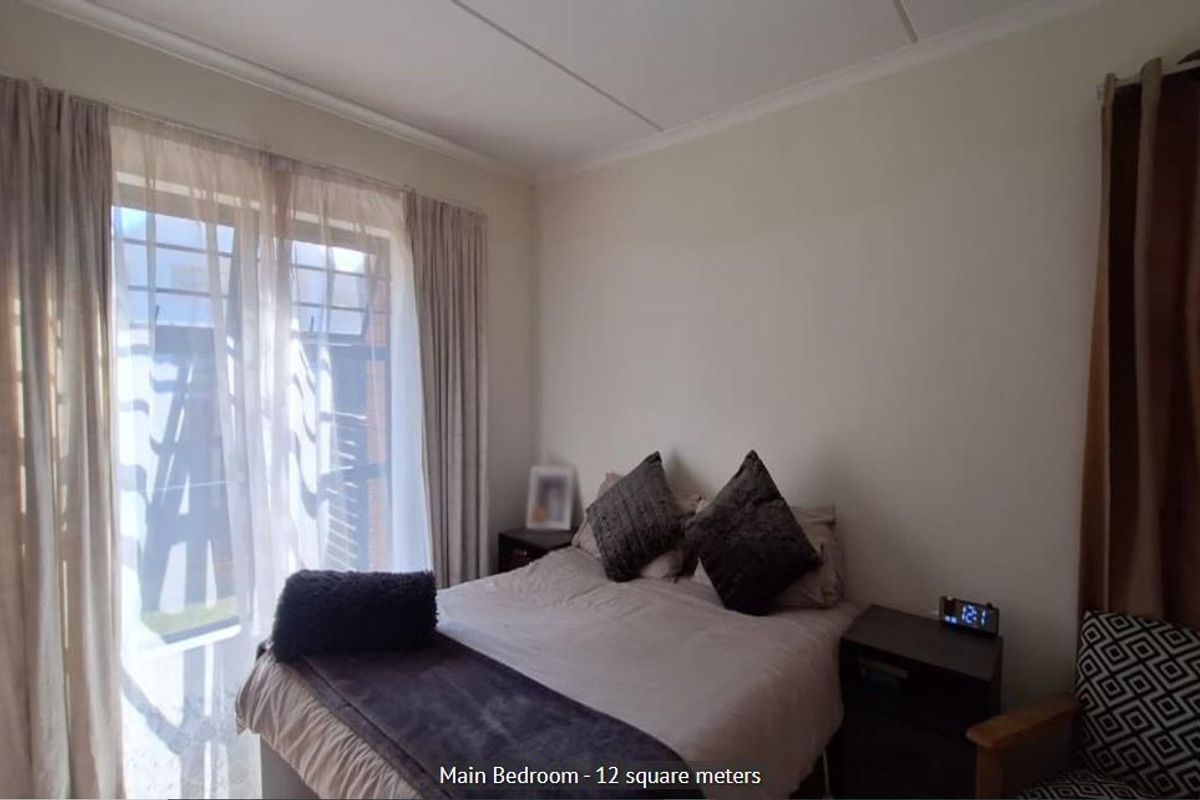 A functional bedroom featuring a sliding glass door with security gate, providing natural light and access to the exterior.