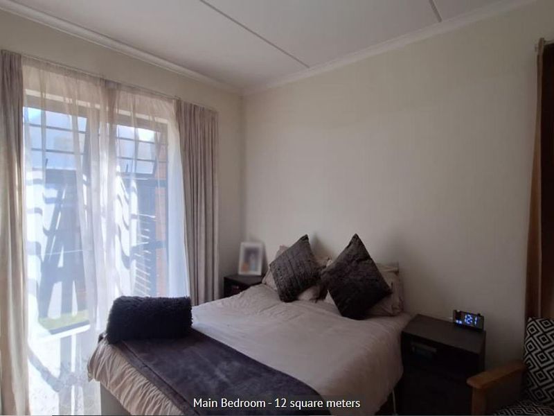 A functional bedroom featuring a sliding glass door with security gate, providing natural light and access to the exterior.