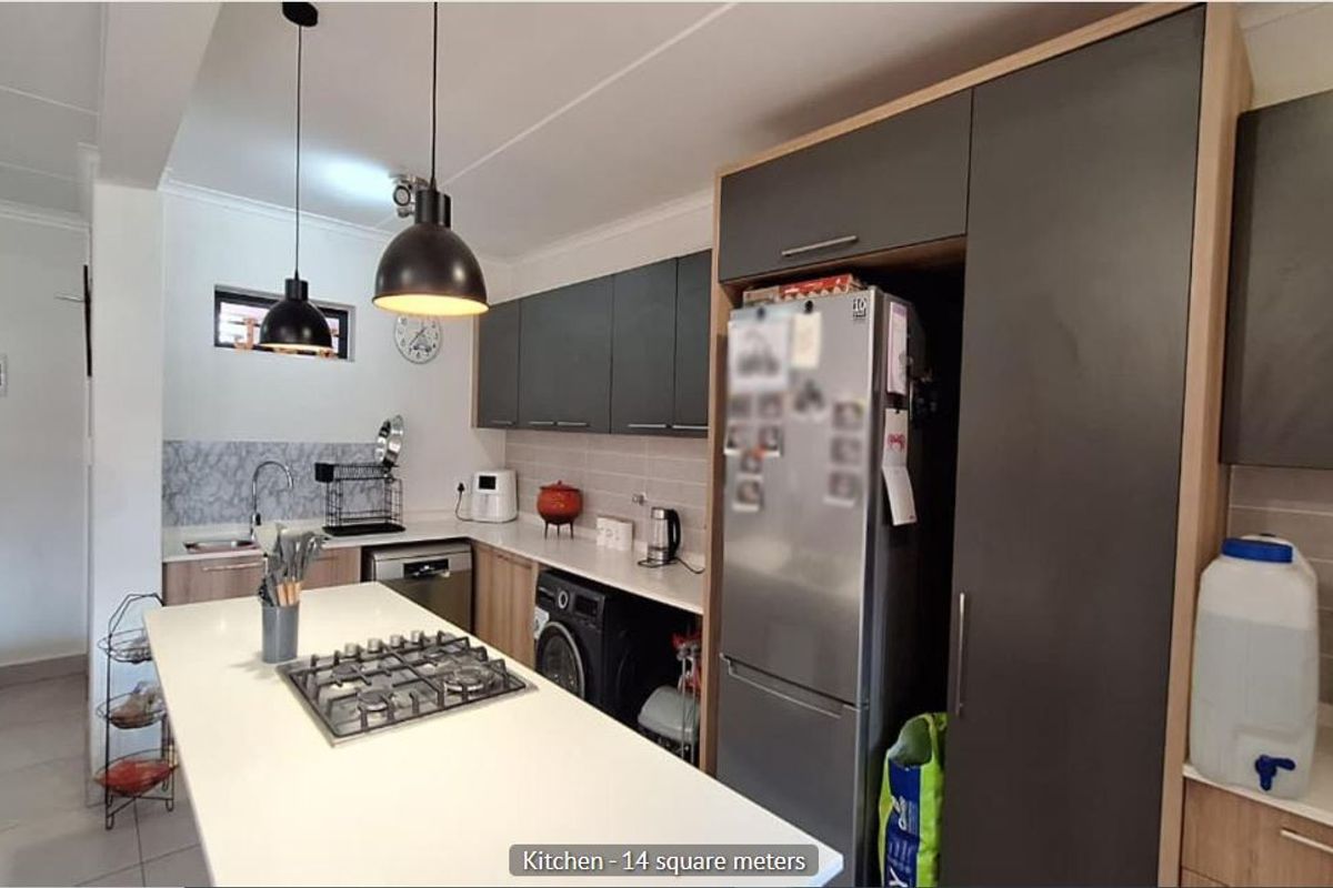 Modern kitchen featuring a central island with a gas hob, sleek cabinetry, tiled backsplash, and integrated sink, offering a functional and contemporary cooking space.