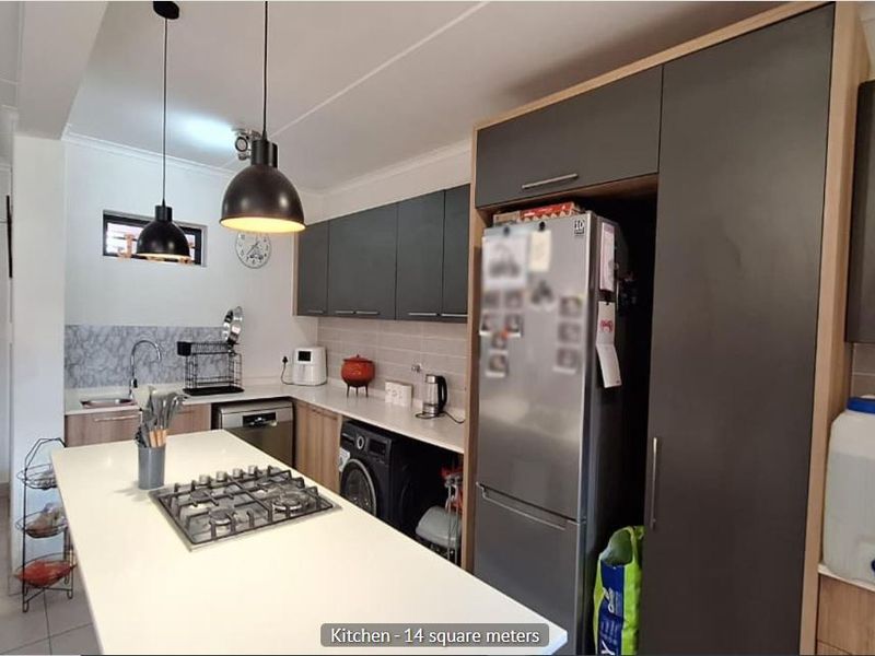 Modern kitchen featuring a central island with a gas hob, sleek cabinetry, tiled backsplash, and integrated sink, offering a functional and contemporary cooking space.